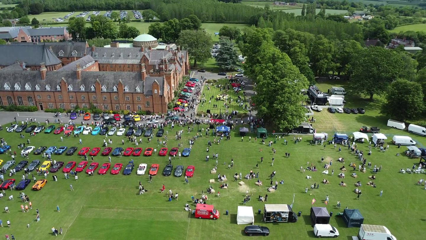 Car gathering and historic building seen from the air