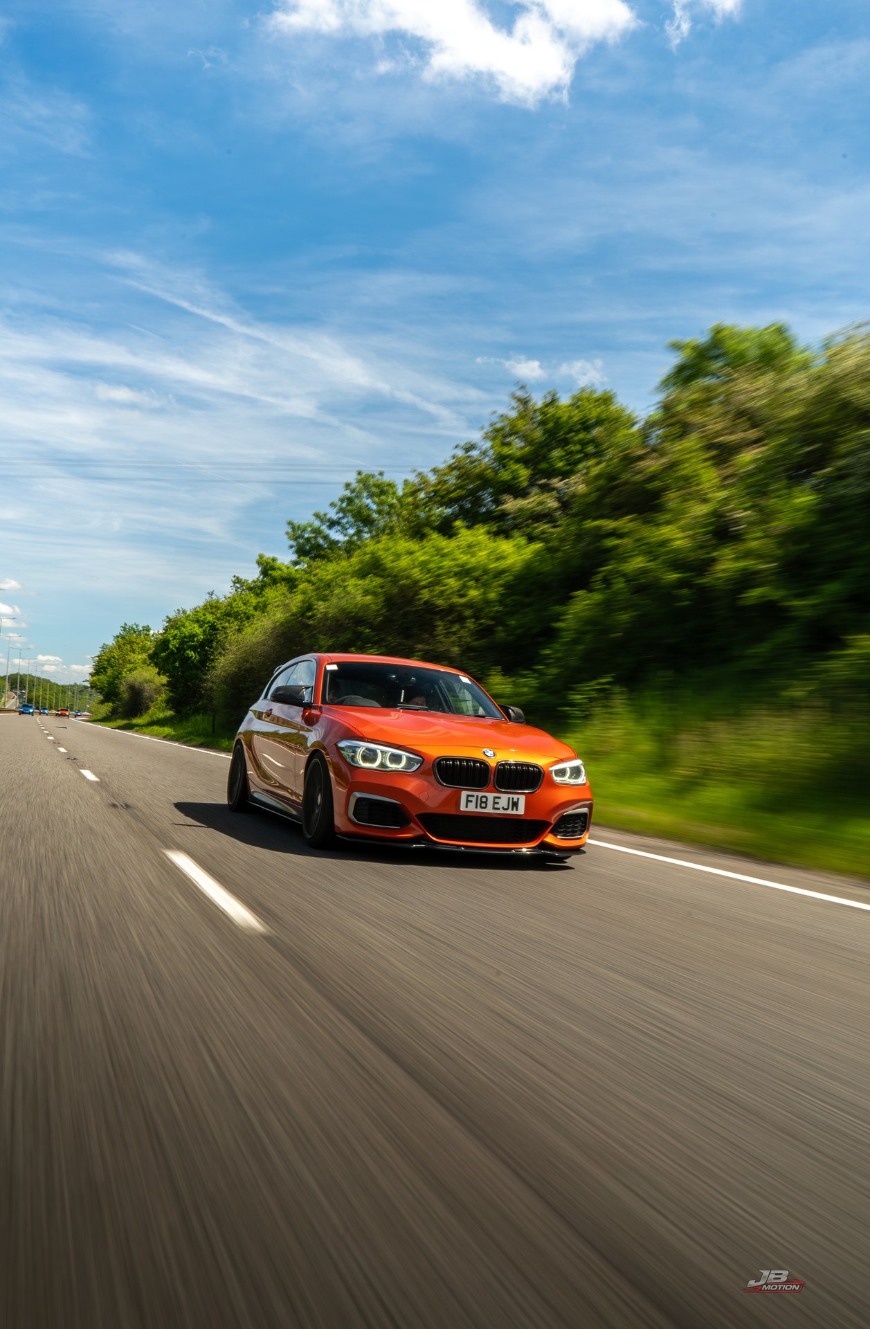 Orange BMW captured in motion on a country road